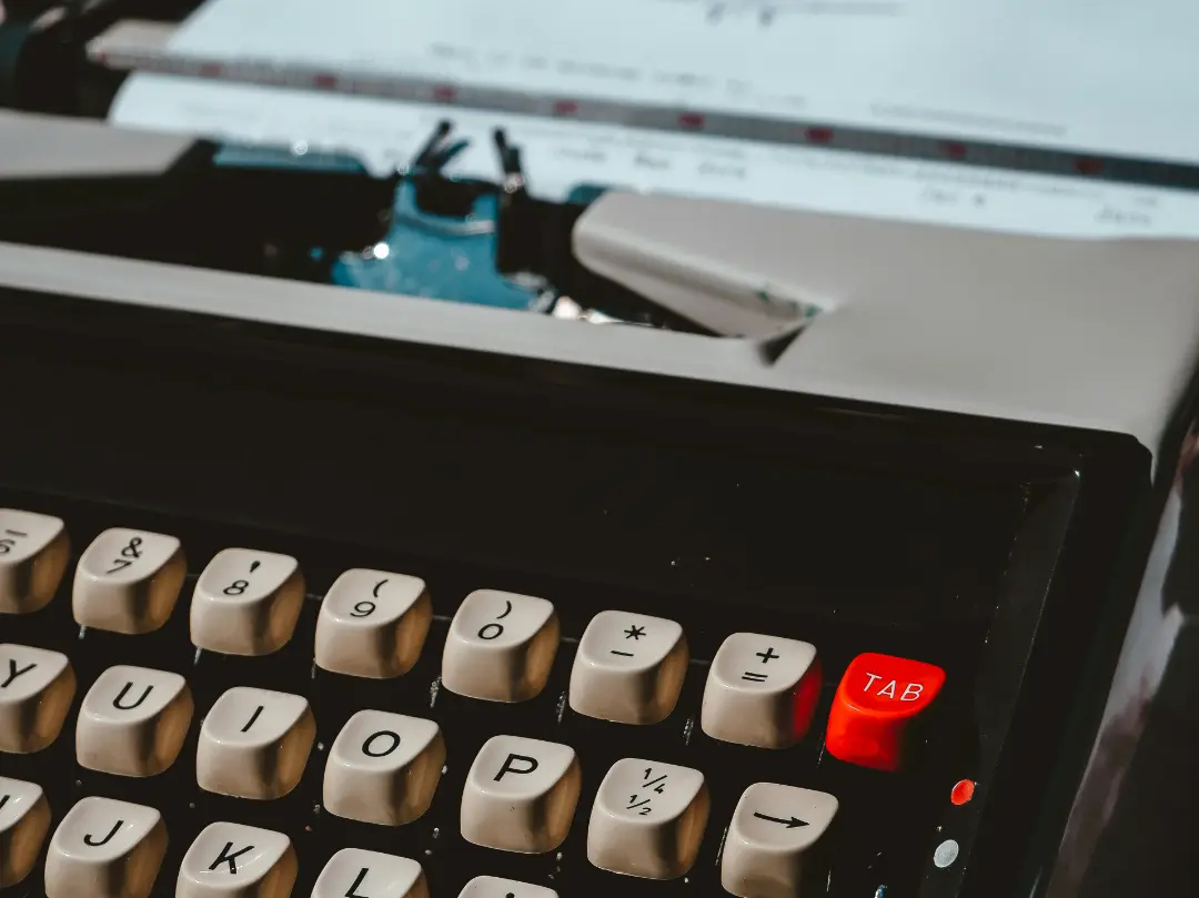 Mechanical typewriter with a red tab key in the top right corner.